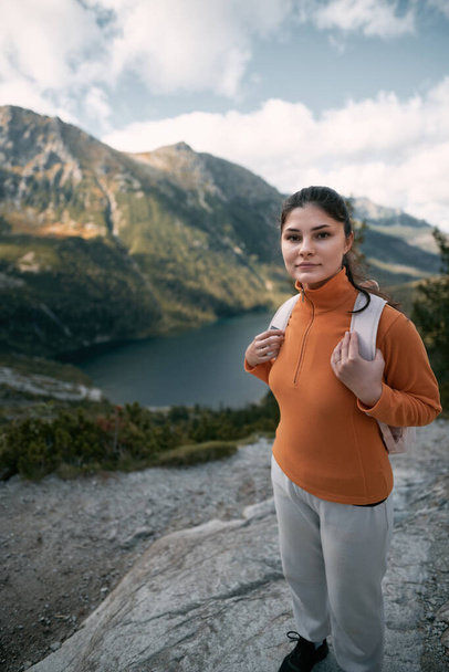 Sporty woman on the top of the mountain. Casual hiking in the mountains. Beautiful sky, lakes, forests and mountain peaks - Photo, Image