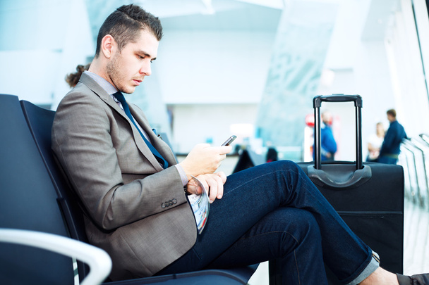 Businessman at airport with smartphone - Zdjęcie, obraz