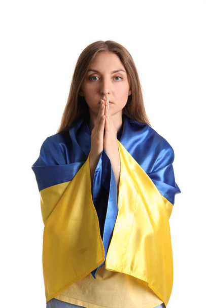 Mujer joven con bandera ucraniana rezando sobre fondo blanco - Foto, imagen