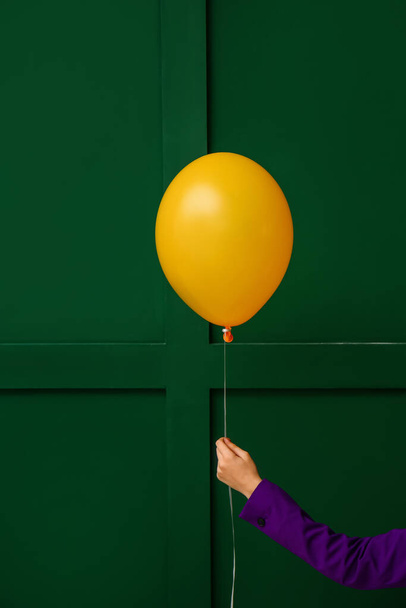 Woman with yellow balloon near green wall - Foto, imagen