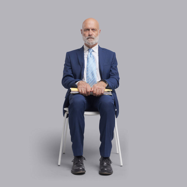 Corporate businessman sitting on a chair and waiting for a meeting or a job interview, business and employment concept - Fotoğraf, Görsel