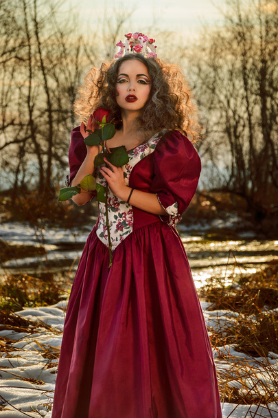 Όμορφο κορίτσι σε vintage κόκκινο φόρεμα με ένα τριαντάφυλλο - Φωτογραφία, εικόνα