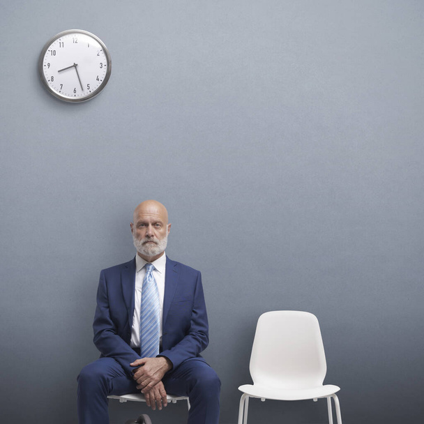 Corporate businessman sitting in the waiting room, he is waiting for a job interview, employment and recruitment concept - 写真・画像