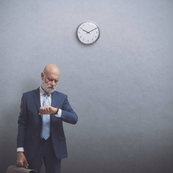 Corporate businessman waiting for a meeting, he is checking the time, copy space - Foto, Imagem