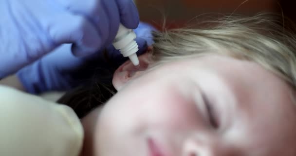 Ai bambini con otite media vengono somministrate gocce antibiotiche nel primo piano dell'orecchio 4k film al rallentatore. Trattamento della malattia dell'orecchio nei bambini concetto - Filmati, video