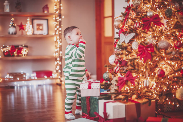 Little boy in pajama standing near the Christmas tree. Concept of the Christmastime and New Year eve. - Valokuva, kuva