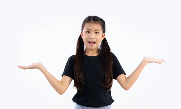 Asian school girl cute kid in black t-shirt posing hand pointing for choosing on white background.	 - 写真・画像