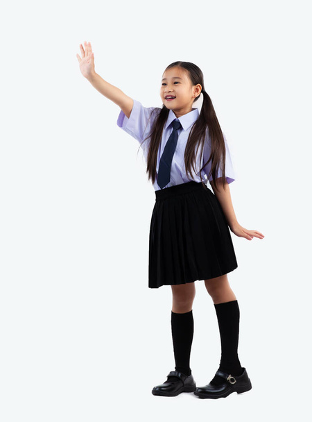 Asian junior school kid in student uniform standing and posing goodbye on white background full length studio shot. Back to school.	 - Φωτογραφία, εικόνα