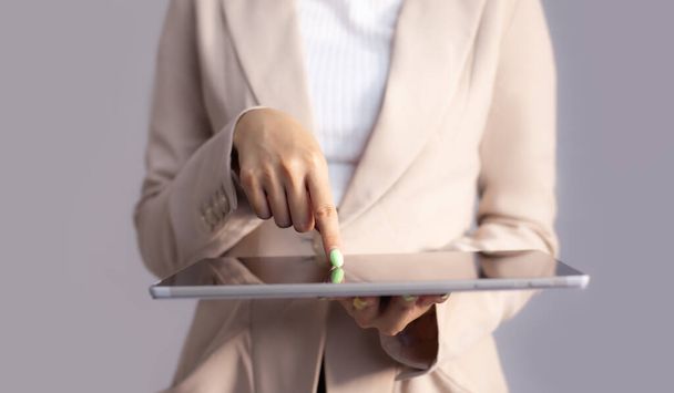 Asian business woman in beige color suit finger pointing and touching on black blank tablet screen.	 - 写真・画像