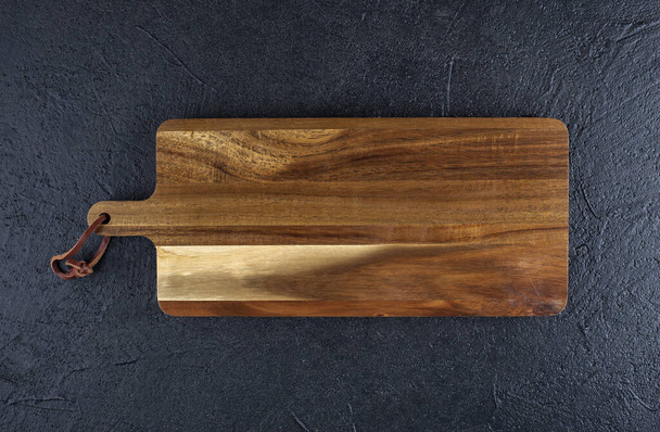 wooden cutting board on a black wooden , copy spce - Photo, Image