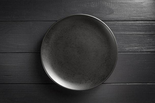 Black plate empty on a black background. - Foto, Imagen