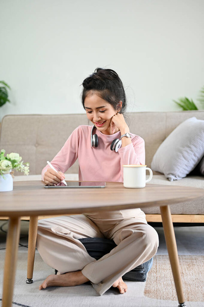 Portré, csinos ázsiai egyetemista lány, aki házi feladatot csinál a nappalijában. Egy nő, aki naplót vagy naplót ír a nappalijában.. - Fotó, kép