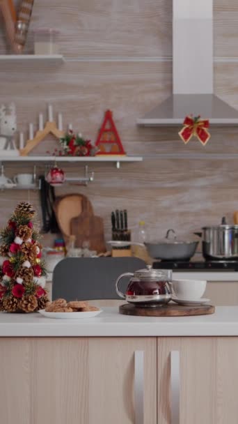 verticale video: Lege kerstversierde keuken met niemand erin is klaar voor het kerstdessert. Op tafel gebakken koekje dessert met kopje koffie te wachten voor gasten tijdens de wintervakantie - Video