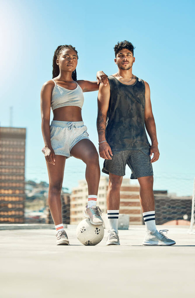 Fitness, football and exercise couple with motivation, workout and sports training in the city. Man and woman athlete with soccer ball after a practice game in a urban town with a blue sky background. - 写真・画像