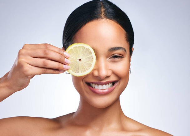 Zorg voor je intellect. Portret van een aantrekkelijke jonge vrouw poseren met een gesneden citroen tegen een grijze achtergrond - Foto, afbeelding