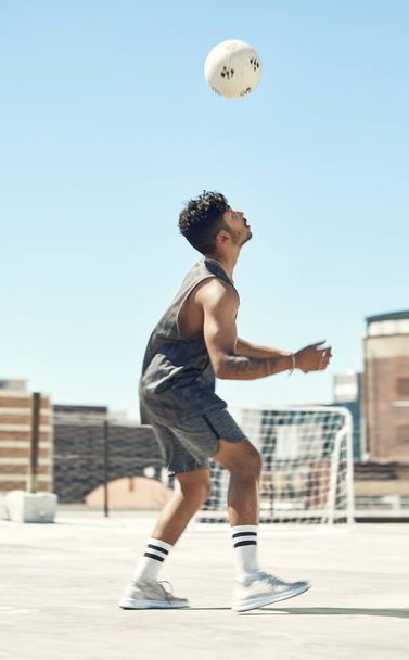 Training, soccer and man with ball in air trick on city rooftop in Brazil for outdoor playing. Football, workout and athlete male practicing technique with focus, concentration and dedication - Фото, зображення