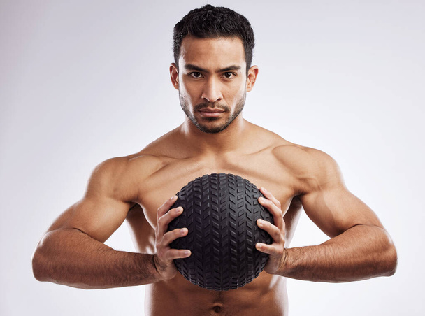 Fitness instruments come in many shapes and sizes. a young man holding a medicine ball against a studio background - 写真・画像