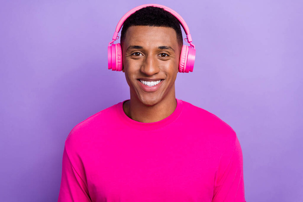 Portret przyjemnego przystojniaka blakną fryzurę nosić różowy t-shirt słuchawki słuchać playlist izolowane na fioletowy kolor tła. - Zdjęcie, obraz