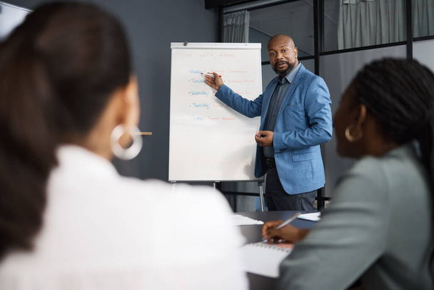 Here are our deadlines for this week. a mature businessman using a whiteboard during a presentation to his colleagues in an office - Foto, Imagem