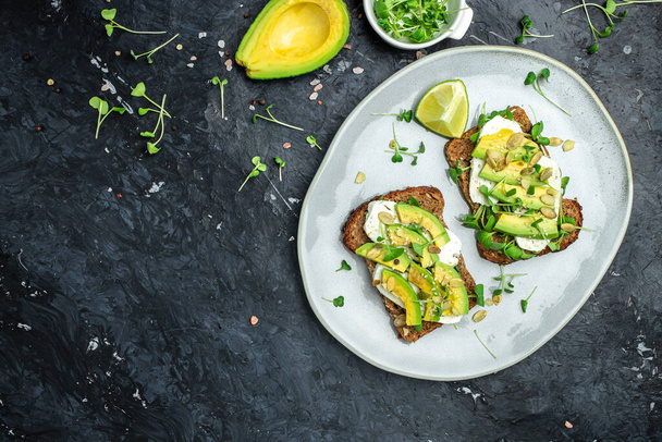 Healthy avocado toasts with rye bread, sliced avocado, cheese, pumpkin, nut and sesame for breakfast or lunch. Vegetarian food. Vegan menu. Food recipe. - Фото, изображение