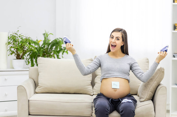 Photo of pregnant woman holding child small clothes. Concept of pregnant woman. - Foto, immagini