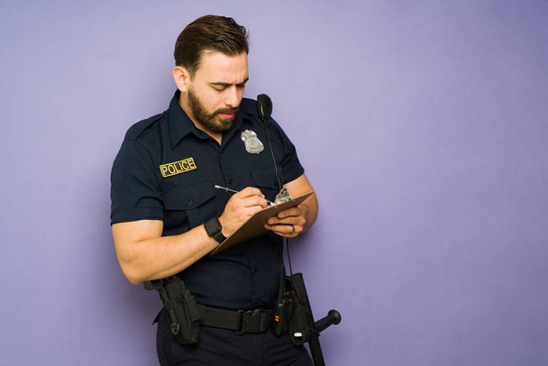 Caucasian police officer on duty writing a parking or traffic ticket  - Photo, Image