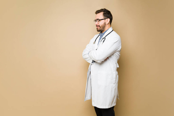 Feliz doctor masculino usando una bata de laboratorio y trabajando en la atención médica contra un fondo de estudio - Foto, imagen