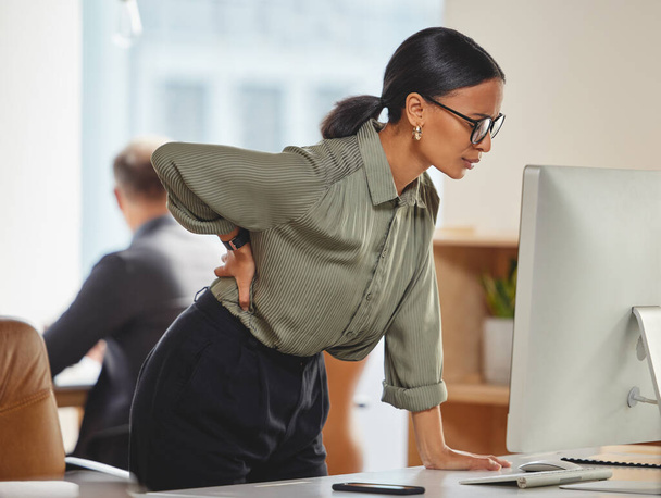 I really need to better my posture when working. a young businesswoman experiencing back pain while working in an office - Photo, image