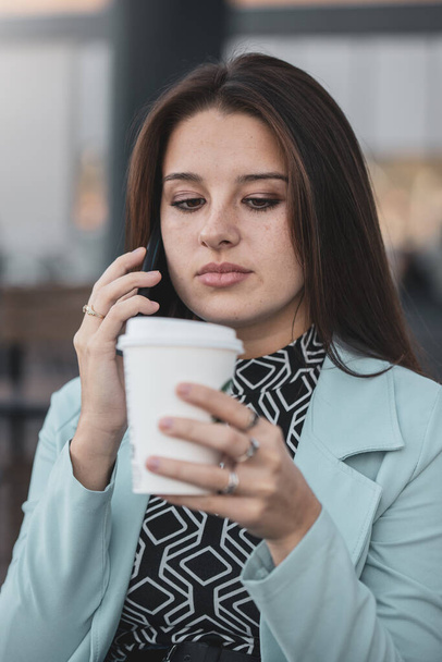 Jovem, mulher linda bebendo um café enquanto fala em seu telefone.  - Foto, Imagem