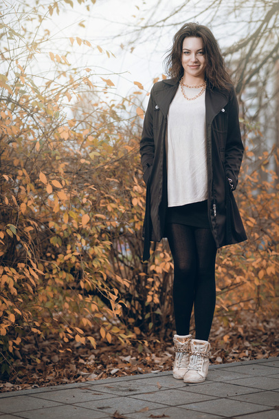 Girl in black coat in autumn in park. - Fotoğraf, Görsel