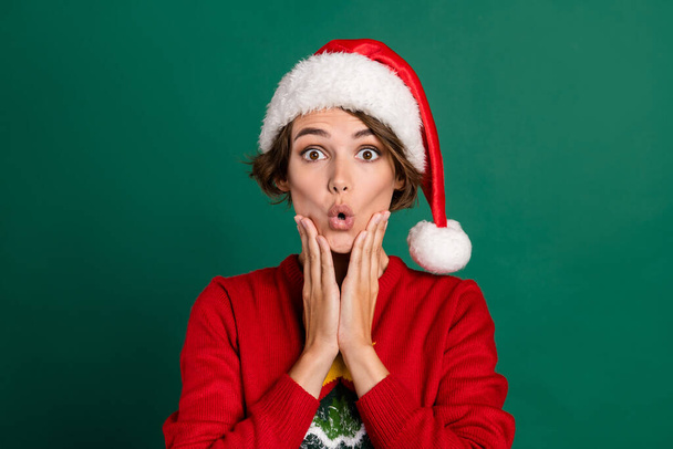 Photo of cheerful impressed lady wear red sweater cap arms cheeks big eyes isolated green color background. - 写真・画像