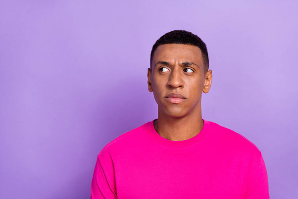 Portrait of interested suspicious curious man with fade hairstyle dressed pink t-shirt look empty pace isolated on violet color background. - Foto, imagen