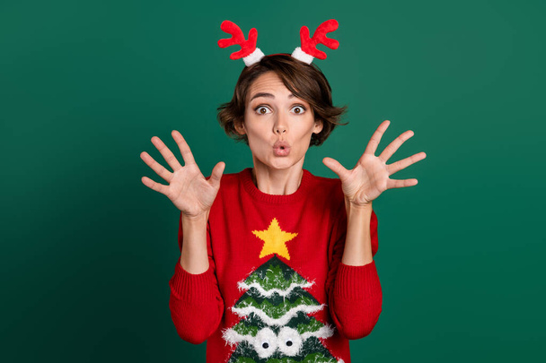 Photo of impressed funky lady wear red sweater horns hair band rising arms isolated green color background. - Photo, image