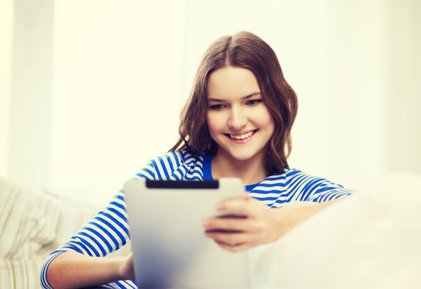 smiling teenage girl with tablet pc at home - Фото, изображение