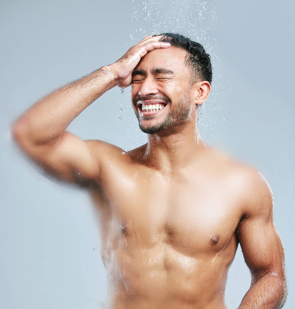 Showers are a great way to energise yourself for the day. Studio shot of a handsome young man taking a shower against a grey background - Photo, Image