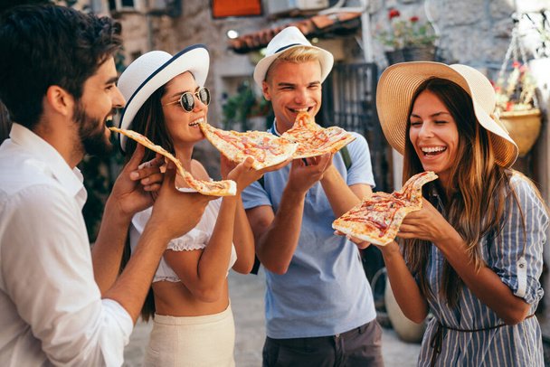 Amigos divirtiéndose al aire libre, comiendo pizza en vacaciones de verano - Foto, imagen