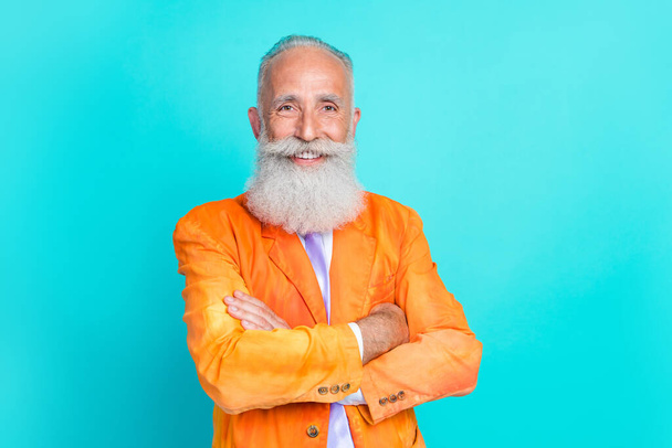 Photo of attractive cheerful retired man dressed bright orange jacket smiling arms folded isolated turquoise color background. - Fotó, kép