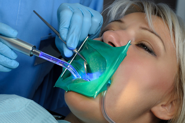 dentist with patient, using dental curing light - Photo, Image
