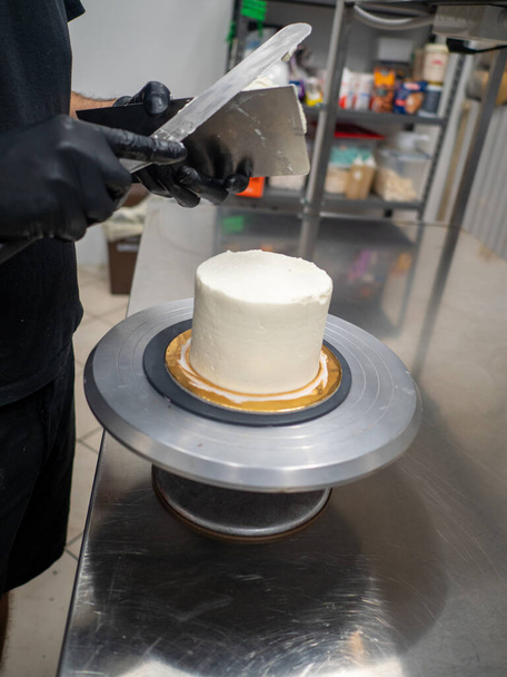 Декоратор з використанням шпателя і скребка для гладкого масляного крему на матовому торті
 - Фото, зображення