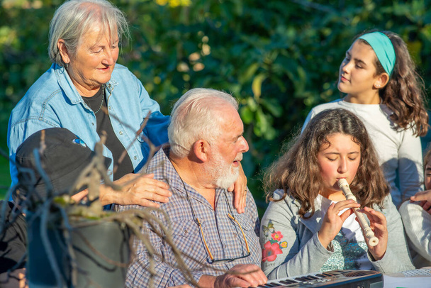 Abuelo jugando al aire libre con sus nietos con instrumentos de música - Foto, Imagen