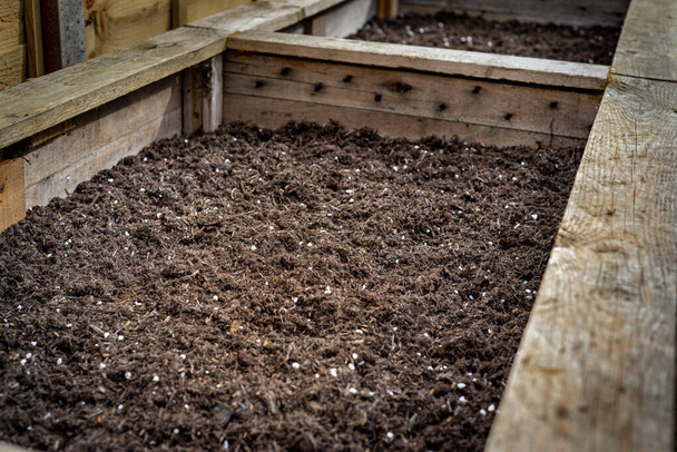 Nahaufnahme von großen hölzernen Pflanzkübel Gemüsekasten Container im Hinterhof Garten mit organischen fruchtbaren Boden bereit für die Pflanzung von Gemüsesamen gefüllt. - Foto, Bild