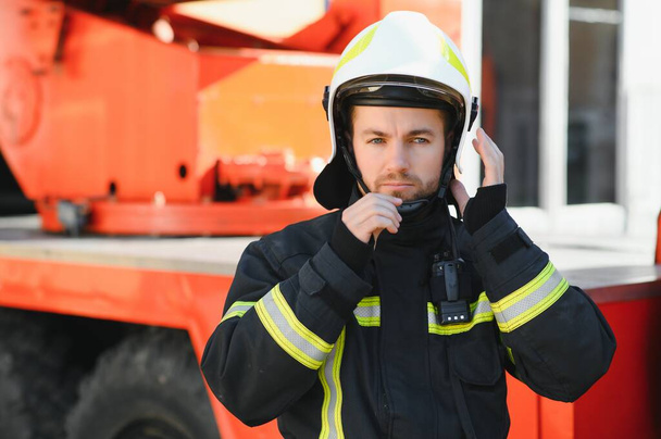 Fireman (firefighter) in action standing near a firetruck. Emergency safety. Protection, rescue from danger - Фото, зображення