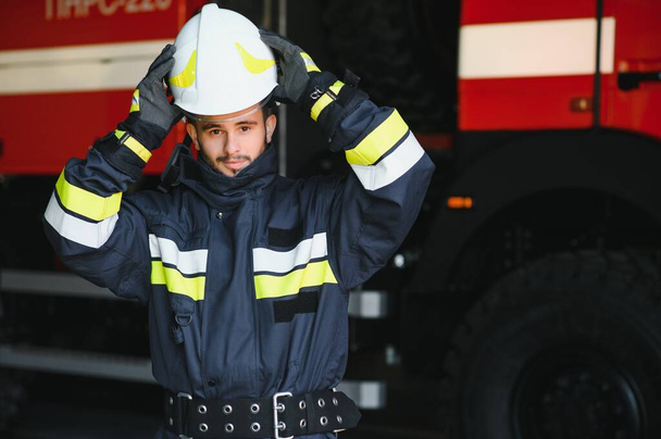 Firefighter portrait on duty. Photo fireman with gas mask and helmet near fire engine - Valokuva, kuva