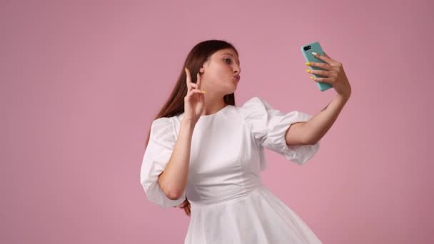 4k video di adolescente femmina prendere selfie isolato su sfondo rosa. Concetto di influencer. - Filmati, video
