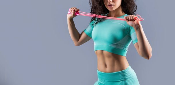 Female athlete crop view in sportswear holding fitness skipping rope studio isolated on grey. Fitness rope workout. Fitness workout, copy space. - Photo, Image