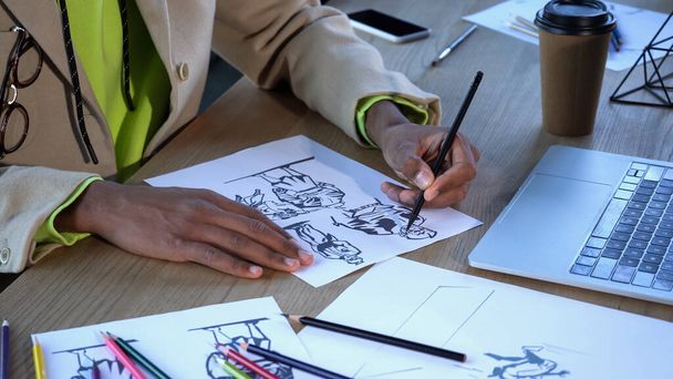 Widok upraw afrykańskiego amerykańskiego projektanta rysunek szkice w pobliżu urządzeń i kubek papieru w studio  - Zdjęcie, obraz