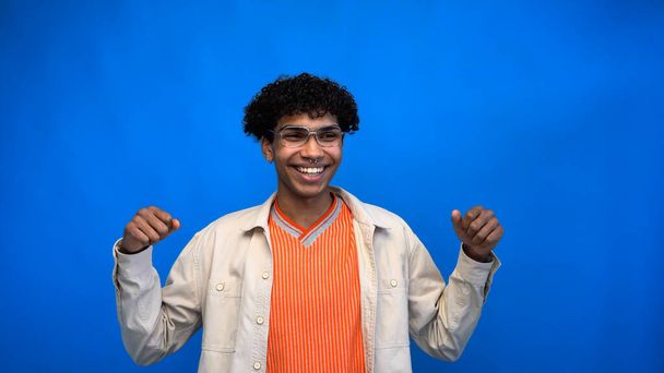 Cheerful african american man in eyeglasses looking away isolated on blue  - Foto, Imagen