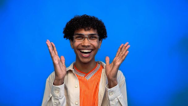Positive and stylish african american man looking at camera on blue background  - 写真・画像