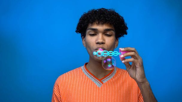Stylish african american man blowing soap bubbles isolated on blue  - Photo, Image