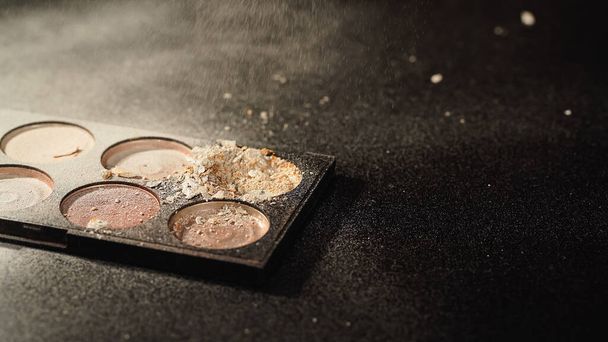 Palette with crushed face powder on black background with copy space - Фото, изображение